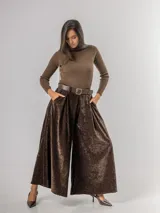 Pantalón tipo palazzo de corte oversized, confeccionado en tela con textura aterciopelada en color negro. Presenta cintura alta con pinzas, bolsillos laterales y un cinturón ancho integrado con hebilla al tono.