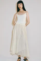 Falda midi fluida de tiro medio, color blanco, con cintura elástica ajustable mediante cordones y bajo asimétrico.