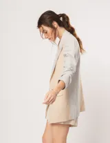 Blazer oversized de corte recto en lino, color beige y gris. Largo a la cadera, con hombreras finitas forradas, costuras internas con sesgo combinado y bolsillos delanteros.