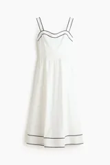 Vestido midi de algodón color blanco, con escote corazón, breteles anchos y espalda con punto smock. Presenta cuerpo entallado, costura fruncida en la cintura y pollera con vuelo, con ribetes negros en contraste en el escote y el bajo.