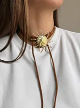 Gargantilla tipo lazo con dije central de sol en bronce con acabado texturizado y tiras largas de cuero marrón.