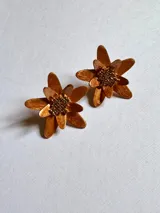 Par de aros dorados con forma de flor, con pétalos texturizados y centro de cuentas pequeñas.