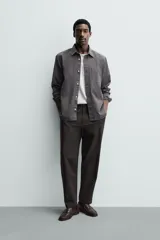 Pantalón de corte regular fit, color negro, confeccionado en tejido elástico. Presenta cintura elástica, cierre frontal con cremallera y botón, bolsillos laterales y bolsillos traseros de vivo.