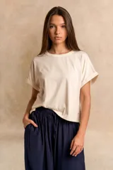 Remera de algodón peinado color crudo, con cuello redondo y mangas cortas con vuelta.