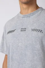 Remera de algodón con efecto de lavado snow-wash en color gris. Presenta un diseño de cuello redondo, mangas cortas y un estampado frontal minimalista con gráficos de estilo automovilístico y cuadros de meta.