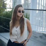 Chaleco corto con estampado abstracto en tonos dorados y azules, escote en V y cierre frontal con botones de madera.