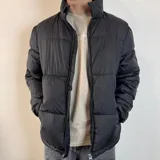 Campera puffer negra con cierre frontal, cuello alto y diseño acolchado horizontal.
