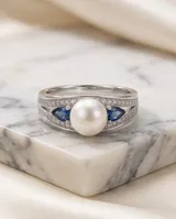 Anillo de plata 925 con una perla central y circonias azules y transparentes en los laterales.