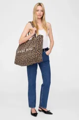 Bolso tipo tote bag grande sin forro de Anine Bing, confeccionado en lona con estampado animal print de serpiente en tonos grises y blancos. Cuenta con doble asa de hombro y el nombre de la marca estampado en contraste en el frente.