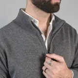 Campera tejida color marrón claro con cierre frontal, cuello alto y mangas largas con puños acanalados.