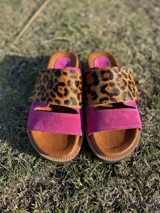 Sandalias bajas con base color suela, tira ancha de cuero fucsia y tira superior de animal print.