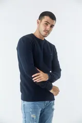 Sweater de punto con textura geométrica, color gris, de cuello redondo y manga larga. Presenta puños y ruedo acanalados con detalle de borde en color oscuro y logo bordado en el pecho.