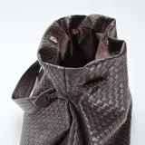 Bolso grande de mano color marrón, con diseño de efecto trenzado y asa superior.