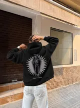 Canguro negro con capucha y bolsillo tipo canguro, confeccionado con felpa suave premium. En la espalda presenta una estampa temática con un esqueleto dentro de un ataúd y las leyendas "Wake Up" y "Kaboa Industries".