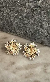 Aros con diseño de flor de dos piezas desmontables, combinando pétalos en tono plateado y dorado. El diseño permite separar las piezas para usar la flor dorada de forma individual.