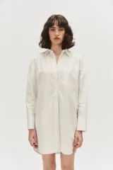 Camisa oversize color blanco, confeccionada en algodón, con cuello clásico, cierre frontal con botones tapados, un bolsillo aplicado en el pecho y mangas largas con puños anchos.