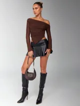 Top marrón con escote off-shoulder, mangas largas transparentes y corte asimétrico.