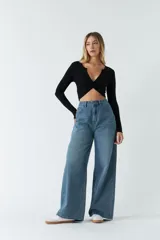 Top de manga larga en tejido rib negro, con escote en V profundo y detalle de nudo frontal que genera un efecto fruncido.