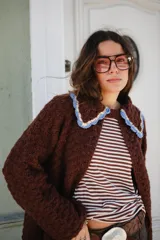 Saco tejido en crochet color marrón, con diseño de textura en relieve, manga larga y cuello grande con bordes en color celeste y crema.