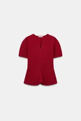 Top peplum confeccionado en hilatura de algodón de color bordó, con escote en V pronunciado, mangas cortas abullonadas y bajo con vuelo.