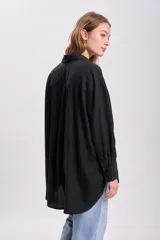 Camisa negra de lyocell con cuello clásico, cierre frontal con botones, manga larga y bolsillo en el pecho.