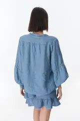 Camisa celeste de lino con botones, mangas largas abullonadas y detalles de crochet en el frente y los puños.