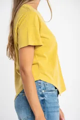 Remera oversize de algodón lavado color mostaza, de manga corta y cuello redondo. Presenta un pequeño bordado en forma de estrella en la parte inferior.