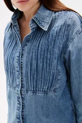 Camisa de jean negro con diseño de frunces verticales en el frente, cuello clásico, cierre frontal con botones y mangas largas con puños abotonados.
