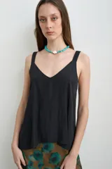 Musculosa de seda color negro, con escote en V y tirantes anchos, de corte fluido y suelto.