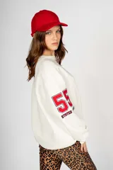 Sweater blanco de algodón con cuello redondo, mangas largas y puños acanalados. Estampado frontal con letras "NYC" y la frase "The City Life".