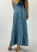 Pollera larga color beige con paneles verticales y ribetes blancos.