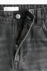 Jean de corte baggy, estilo holgado con piernas rectas, confeccionado en denim de algodón color gris oscuro con efecto lavado. Cuenta con tiro estándar, trabillas para cinto, cierre frontal con botón y cinco bolsillos clásicos.
