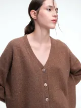 Cardigan de punto color marrón con textura jaspeada, escote en V, cierre frontal con botones y diseño de hombros caídos.