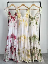 Vestido largo confeccionado en mezcla de tencel y lino, con fondo off white y estampado floral en tonos rosados, rojos y verdes. Cuenta con escote en V pronunciado, breteles anchos ajustables con lazos en los hombros, corte bajo el busto y falda amplia con volados escalonados.