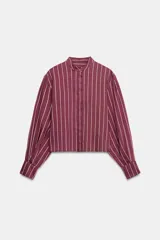 Camisa de cuello subido y manga larga con puños anchos, confeccionada en tejido satinado con diseño de rayas verticales.