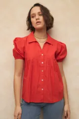 Camisa roja con cuello clásico, mangas cortas abullonadas y cierre frontal con botones.