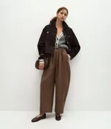 Pantalón barrel de algodón color marrón, con cintura alta, pliegues delanteros, perneras amplias y bajo afinado, diseñado con presillas y un cinturón incluido.