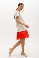 Vestido corto color crudo con rayas horizontales, cuello redondo con volados rojos, corte imperio y falda roja con volados.