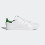 Championes Adidas Stan Smith, modelo clásico de corte bajo, color blanco con detalles en verde. Presentan una parte superior de cuero sintético, perforaciones laterales en lugar de las tres franjas y talón en color verde con logo.