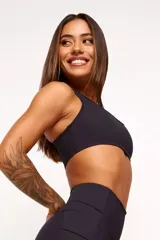 Top deportivo negro con diseño nadador, entrada para almohadillas removibles, bolsillo trasero y detalle reflectivo.