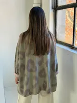 Sweater de punto con diseño animal print difuminado en tonos verdes y grisáceos, de corte holgado, cuello redondo y mangas largas con puños vueltos en color liso.