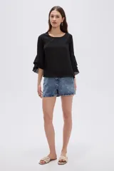 Blusa negra de poliéster, con cuello redondo, mangas 3/4 con volados en capas y diseño holgado.