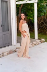 Conjunto de dos piezas en color beige, compuesto por un top strapless con corte asimétrico y un pantalón de corte recto y holgado.