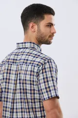 Camisa sport de manga corta con estampa a cuadros en tonos azules, blancos, grises y amarillos, cuello con botones y cierre frontal abotonado.