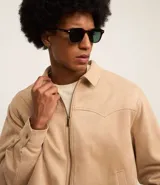 Campera masculina de estilo casual con cuello inglés, cierre frontal por cremallera, bolsillos laterales y ajuste elástico en el bajo. Presenta detalles de recortes en la parte superior delantera.