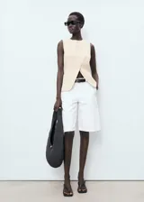 Chaleco de corte recto y diseño sin mangas, con cuello redondo y tirantes anchos. Presenta un cierre frontal con botones y forro interior de algodón.