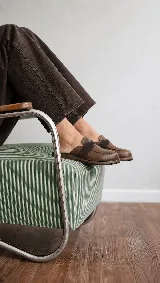 Zueco de cuero marrón, con diseño inspirado en mocasines, tira elástica en el empeine y suela plana confortable.