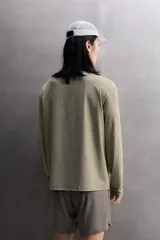 Camiseta de entrenamiento regular fit color gris oscuro, confeccionada en tejido técnico ligero y elástico con estructura. Cuenta con cuello redondo, manga larga y logo estampado en el bajo.