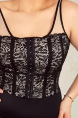 Body colaless negro con puntilla blanca y breteles regulables transparentes. Tiene ganchos reforzados en la parte delantera y broches en la entrepierna con fundillo de algodón.