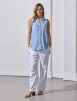 Camisa sin mangas color beige, marca Zac & Rachel, confeccionada en lino. Presenta escote en V, abertura frontal con botones, dos bolsillos delanteros y terminación con botones en los laterales.